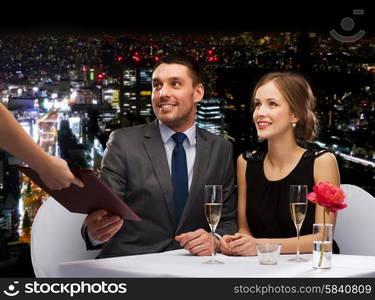 restaurant, couple and holiday concept - waiter giving menu to happy couple at restaurant