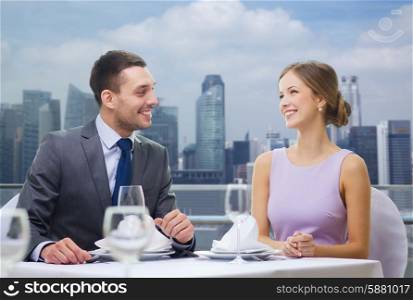 restaurant, couple, dating and holidays concept - smiling couple looking at each other and talking at restaurant