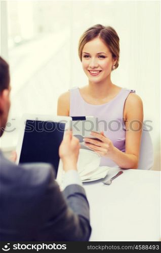 restaurant, couple, technology and holiday concept - smiling couple with menus on tablet pc computers at restaurant