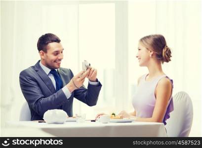 restaurant, couple, technology and holiday concept - smiling man taking picture of wife or girlfriend with digital camera at restaurant. smiling man taking picture with digital camera