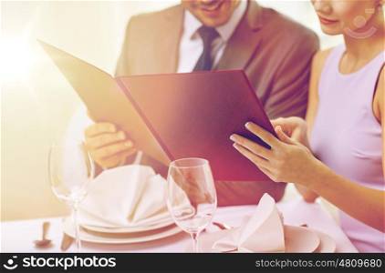 restaurant, food, eating and holiday concept - close up of happy couple with menu choosing dishes at restaurant