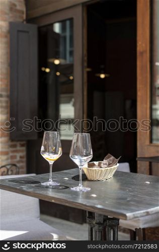 Restaurant on italian street. Two empty glasses of wine on table.