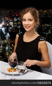 restaurant, people and holiday concept - smiling young woman eating main course at restaurant