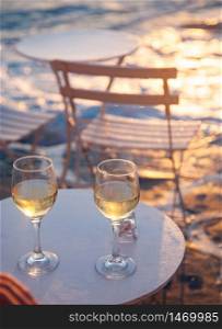 restaurant table by the sea with white wine at sunset summer holiday concept