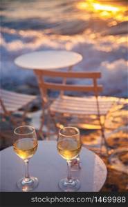 restaurant table by the sea with white wine at sunset summer holiday concept