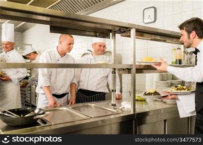 Restaurant waiter take meals from professional cook stainless kitchen