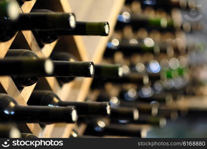 Resting wine bottles stacked on wooden racks in cellar