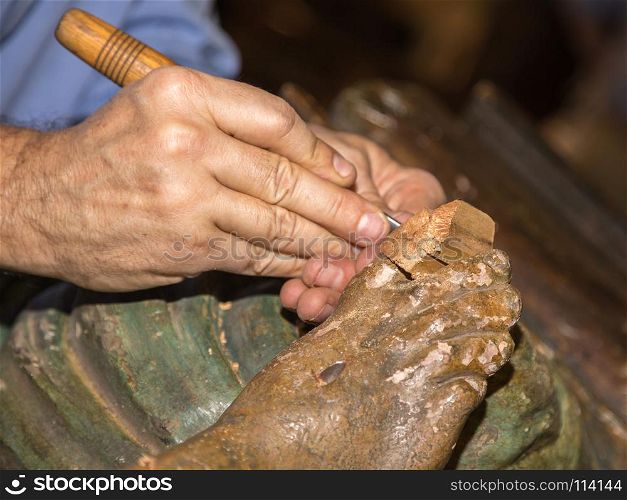 Restoring Wooden Sculpture: Close-up of Restorer working on Religious Works. Restoring Wooden Sculpture: Close-up of Restorer working on Reli