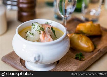 Restourant serving dish - salmon soup on wooden board with pie, drink on table