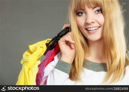 Retail and sale. Blonde girl fashionable woman buying clothes. Client customer holding hangers with vivid color clothing