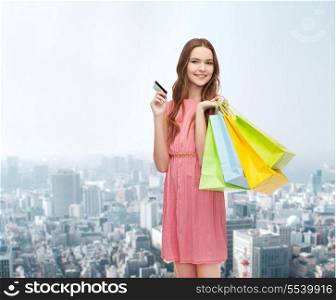 retail and sale concept - smiling woman in dress with many shopping bags and credit card