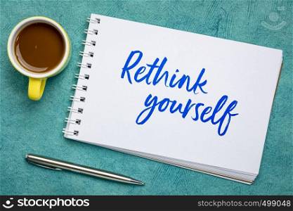 rethink yourself - advice or reminder note, handwriting in a spiral art sketchbook against against textured bark paper with a cup of coffee