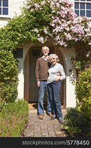 Retired Couple Standing Outside Pretty Cottage