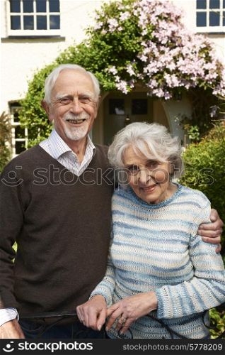 Retired Couple Standing Outside Pretty Home