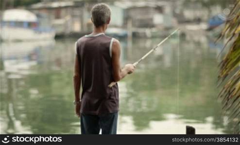 Retired elderly people and leisure activity, old man fishing near the sea. Dolly shot