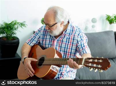 Retired man playing guitar at home