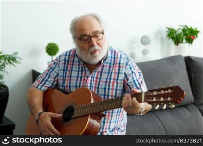 Retired man playing guitar at home