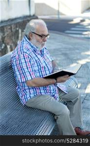 Retired man reading a book in the street