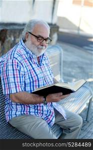 Retired man reading a book in the street