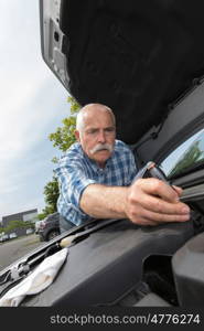 retired man servicing his car engine