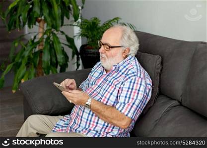 Retired man with white beard and a mobile in his home