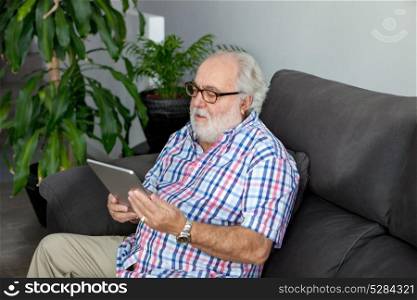 Retired man with white beard sitting on the sofa in his home