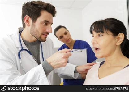 retired patient opening his mouth while doctor checks his throat