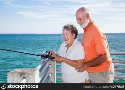 Retired senior couple enjoys fishing together from a pier in Florida.