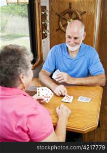 Retired senior couple playin a game of cribbage in the kitchen of their motor home.