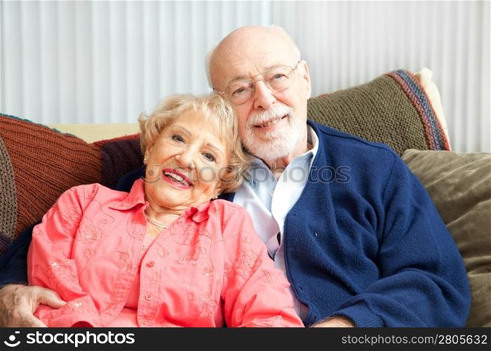 Retired senior couple relaxing together on their living room sofa.