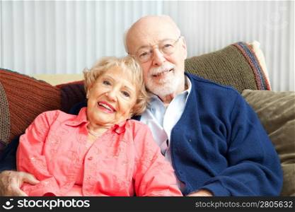 Retired senior couple relaxing together on their living room sofa.