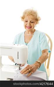 Retired senior lady enjoys sewing in her spare time. Isolated on white.