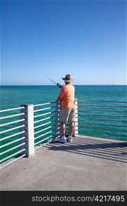 Retired senior man enjoys fighing from a pier.