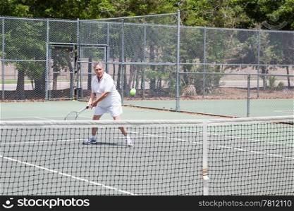 Retired senior woman plays tennis for fun and exercise.