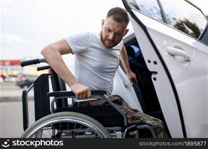 Retired veteran independently transfers from a car to a wheelchair. Paralyzed people and disability, handicap overcoming. Disabled male person. Retired veteran transfers from car to wheelchair