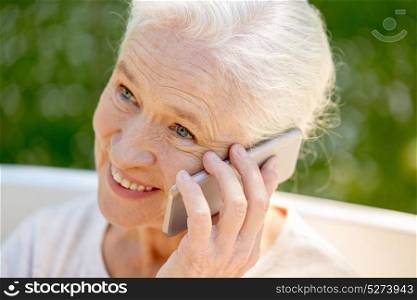 retirement, communication and old people concept - close up of happy senior woman calling on smartphone in summer. happy senior woman calling on smartphone in summer