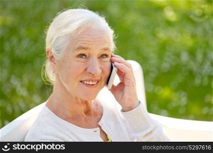 retirement, communication and old people concept - happy senior woman calling on smartphone in summer. happy senior woman calling on smartphone in summer
