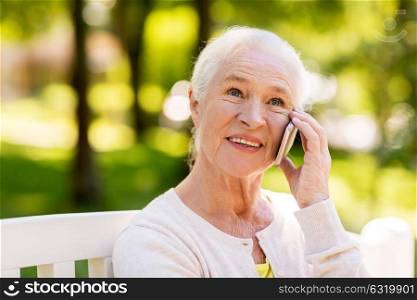 retirement, communication and old people concept - happy senior woman calling on smartphone in summer. happy senior woman calling on smartphone in summer