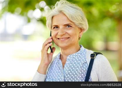 retirement, communication and old people concept - happy senior woman calling on smartphone in summer. senior woman calling on smartphone in summer