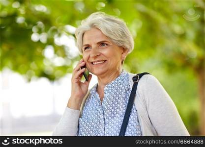 retirement, communication and old people concept - happy senior woman calling on smartphone in summer park. senior woman calling on smartphone in summer park