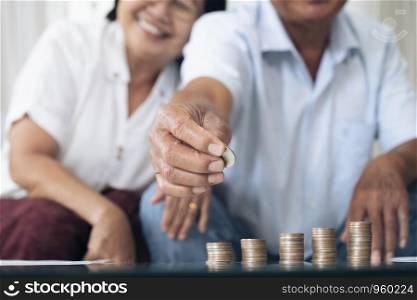 Retirement saving planning. Happy senior couple holding a coin to arrange in a row.