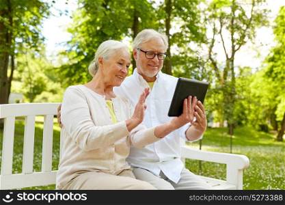 retirement, technology and old people concept - happy senior couple with tablet pc computer at summer park. happy senior couple with tablet pc at summer park