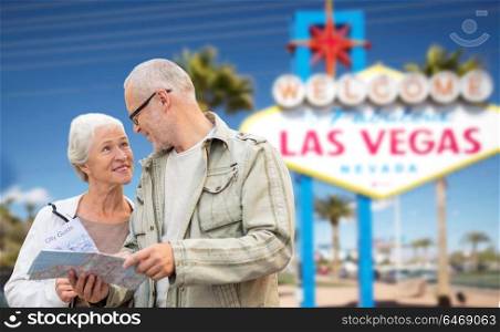 retirement, vacation, tourism and travel concept - happy senior couple with map and city guide over welcome to fabulous las vegas sign background. senior couple with map travelling to las vegas