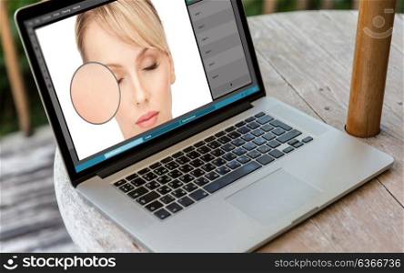 retouch, technology and design concept - laptop computer with woman face image in graphics editor on table. laptop with woman face retouch in graphics editor