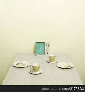 Retro 50&acute;s table setting with dishes coffee cups and vintage clock radio.