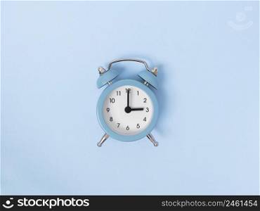 Retro alarm clock middle of blue background. Monochrome simple flat lay with pastel texture. Time concept. Stock photography.. Retro alarm clock middle of blue background. Monochrome simple flat lay with pastel texture. Time concept. Stock photo.