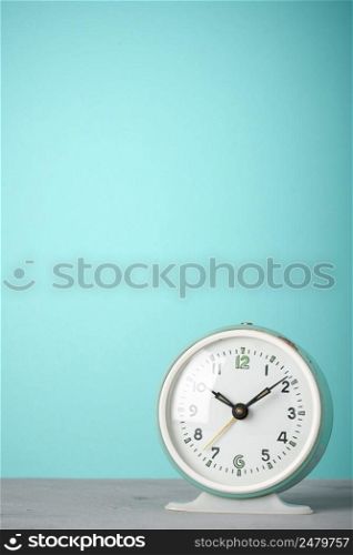 Retro alarm clock on desk blue background vertical copy-space
