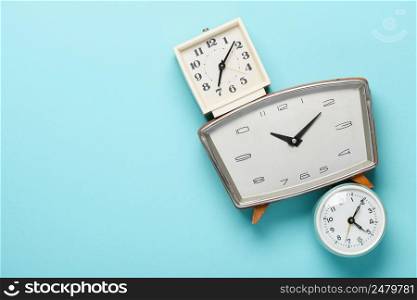 Retro alarm clocks on blue pastel background time concept flat lay top view with copy space