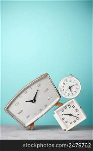 Retro alarm clocks tilted and stacked time concept on vintage blue background