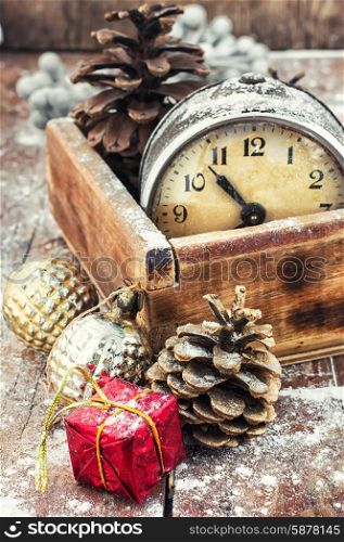 retro arrangement for Christmas with an old alarm clock. outdated watch in wooden box on the background of Christmas decorations and pine cones.